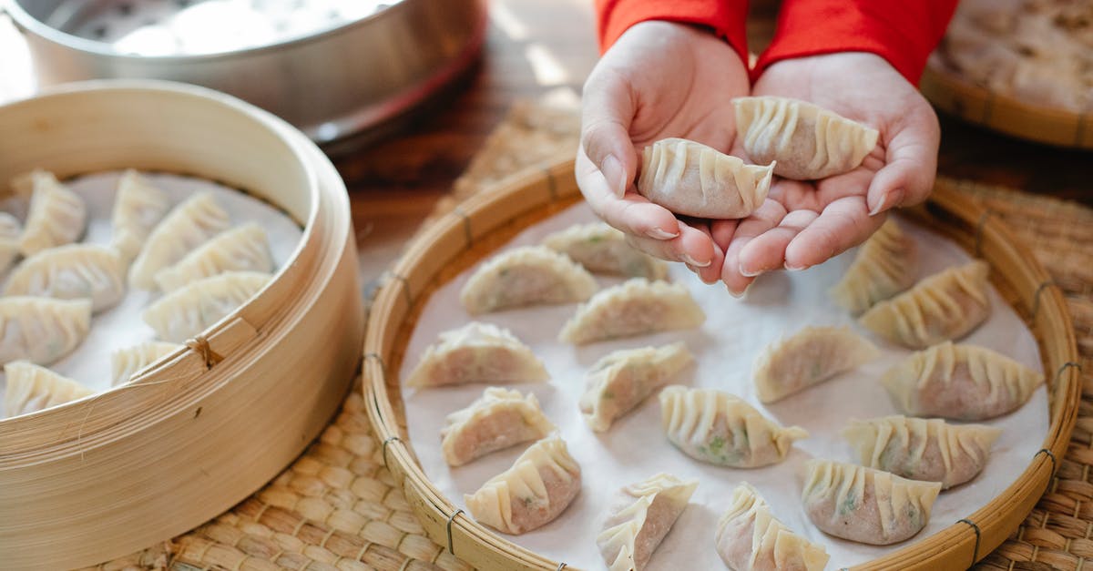 What is the name of the Chinese dish from the movie "Girl with a Pearl Earring"? - From above of crop anonymous female chef demonstrating traditional raw Asian dumplings before serving on tray in kitchen