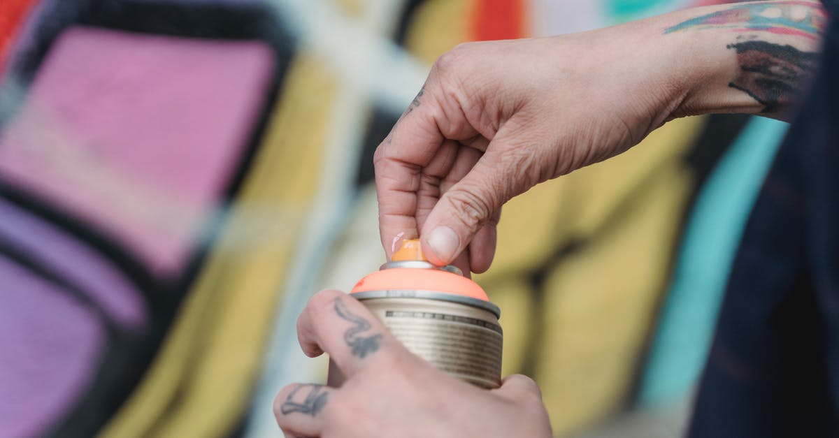 What is the proper way to maintain a can opener? - Soft focus of crop unrecognizable painter with tattoos opening spray paint can while standing near colorful wall with creative graffiti What is the proper way to maintain a can opener? - Soft focus of crop unrecognizable painter with tattoos opening spray paint can while standing near colorful wall with creative graffiti