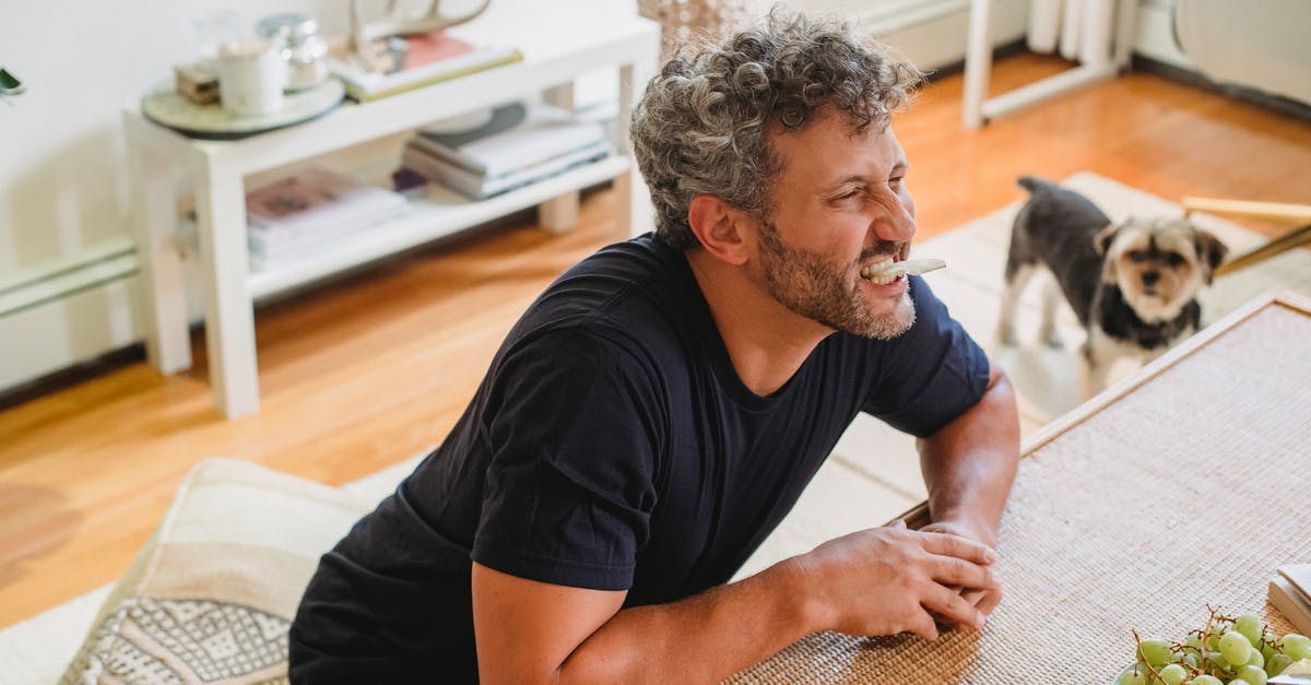 What is the proper way to make a fruit purée? - Cheerful adult male with beard and grey curly hair making faces with piece of apple in teeth What is the proper way to make a fruit purée? - Cheerful adult male with beard and grey curly hair making faces with piece of apple in teeth