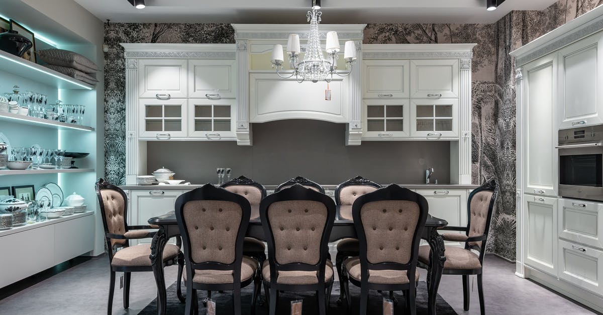 What is the purpose of the storage beneath an oven? - Chairs at table placed in spacious kitchen with oven near white cabinets and storage cupboard with various tableware in apartment What is the purpose of the storage beneath an oven? - Chairs at table placed in spacious kitchen with oven near white cabinets and storage cupboard with various tableware in apartment