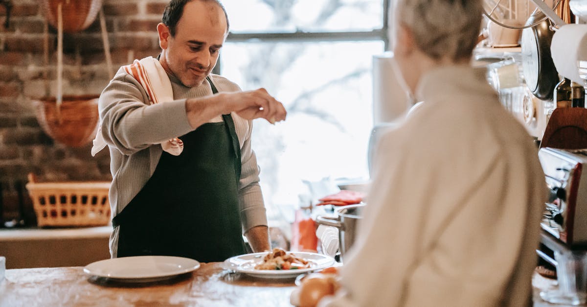 What is the relationship between salt and iodine? - Man cooking food on counter in kitchen near woman What is the relationship between salt and iodine? - Man cooking food on counter in kitchen near woman