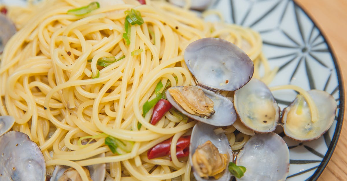 What is the spicy kick in "Kraft Tangy Spaghetti" box meal? - From above of yummy spaghetti with seafood topped with green onion and red pepper served on plate placed on wooden table