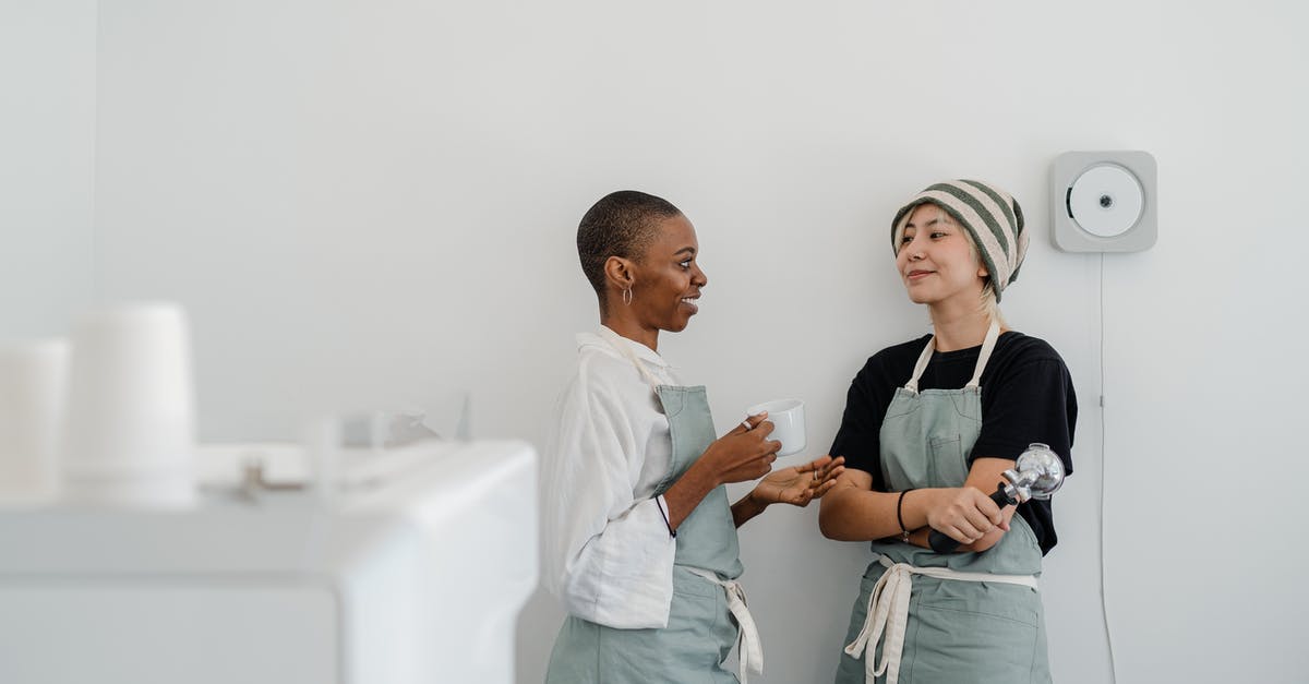 What is this black stuff coming off my George Forman grill? - Couple of multiracial female baristas wearing apron standing near wall in modern coffee shop with minimal interior while drinking coffee and communicating and looking at each other What is this black stuff coming off my George Forman grill? - Couple of multiracial female baristas wearing apron standing near wall in modern coffee shop with minimal interior while drinking coffee and communicating and looking at each other