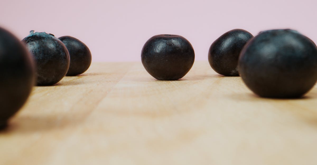 What is this fruit, anyone knows? - Black Round Fruit on Brown Wooden Table What is this fruit, anyone knows? - Black Round Fruit on Brown Wooden Table
