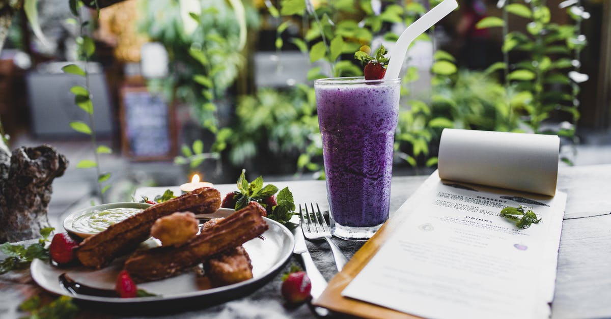 What is this Spanish dessert? - Glass of yummy blueberry milkshake with straw near plate of churros with fresh strawberries and menu with cutlery on table in front of climbing plant in restaurant What is this Spanish dessert? - Glass of yummy blueberry milkshake with straw near plate of churros with fresh strawberries and menu with cutlery on table in front of climbing plant in restaurant