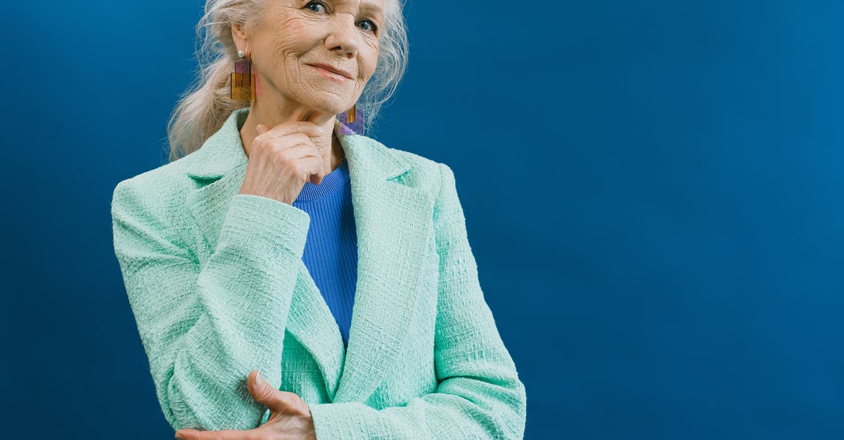 What kind of bread lasts long? - Elderly smiling gray haired female wearing mint blazer and earnings standing against blue background touching chin and looking at camera What kind of bread lasts long? - Elderly smiling gray haired female wearing mint blazer and earnings standing against blue background touching chin and looking at camera