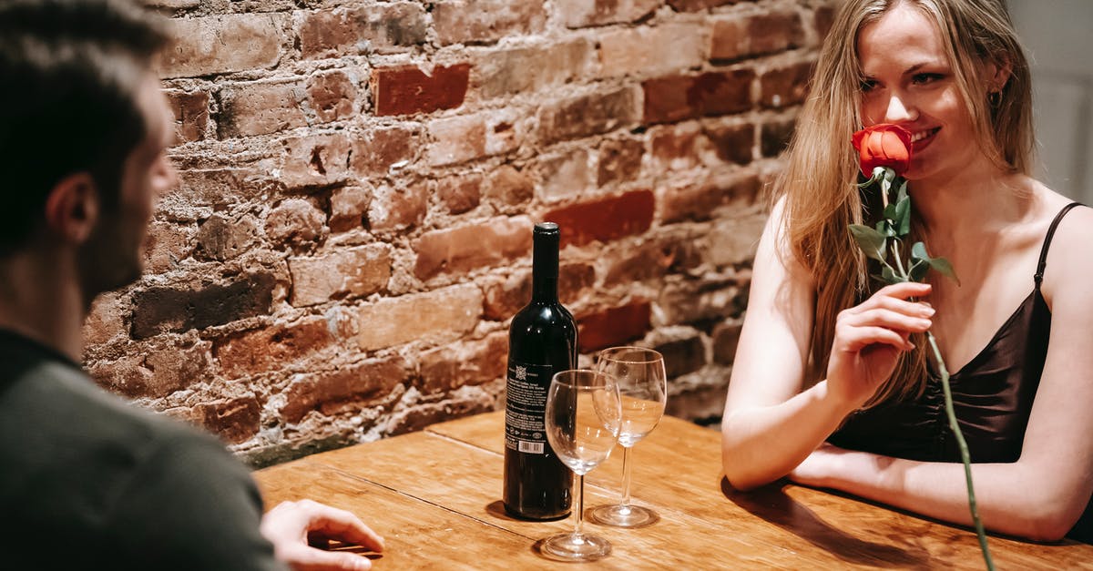 What made these red lentils 'brick' together? - Young couple in elegant clothes sitting at wooden table near brick wall in light restaurant while enjoying date with red rose and wine near glasses and looking at each other What made these red lentils 'brick' together? - Young couple in elegant clothes sitting at wooden table near brick wall in light restaurant while enjoying date with red rose and wine near glasses and looking at each other