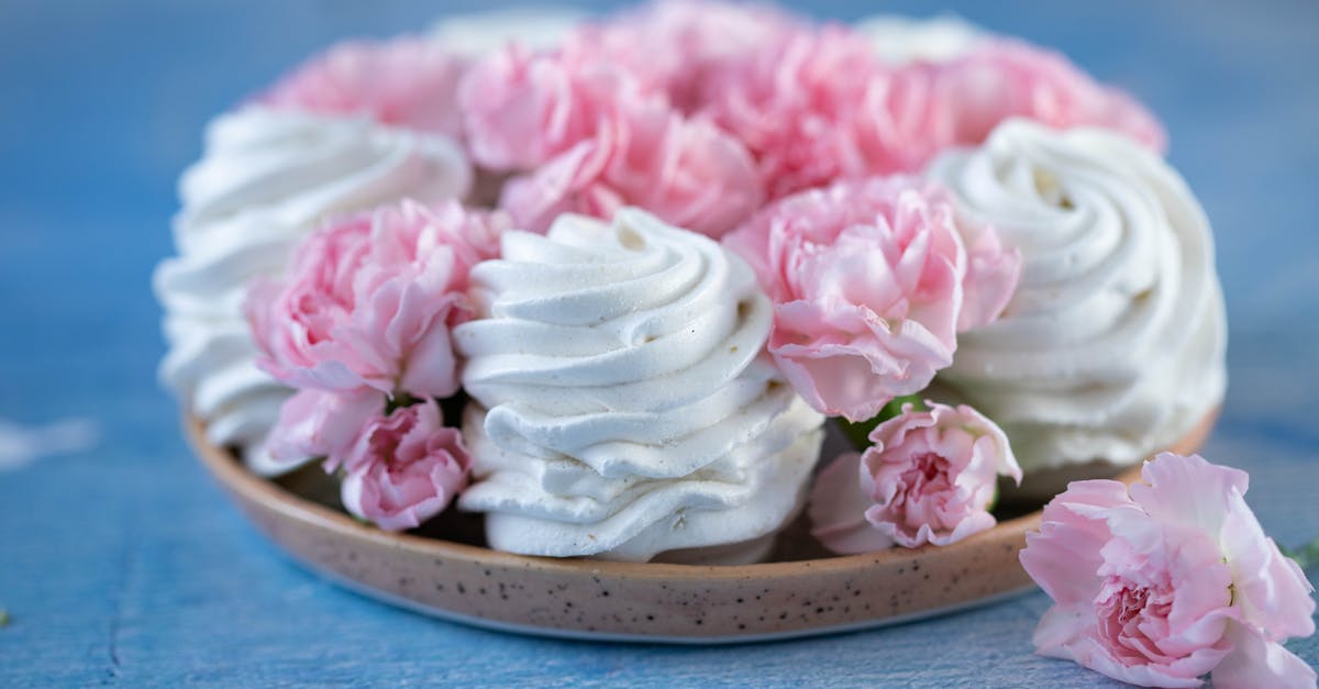 What makes a souffle rise? - From above of delicious white marshmallows zephyr and buds of pink flowers placed on plate on blue table in room against blurred background What makes a souffle rise? - From above of delicious white marshmallows zephyr and buds of pink flowers placed on plate on blue table in room against blurred background