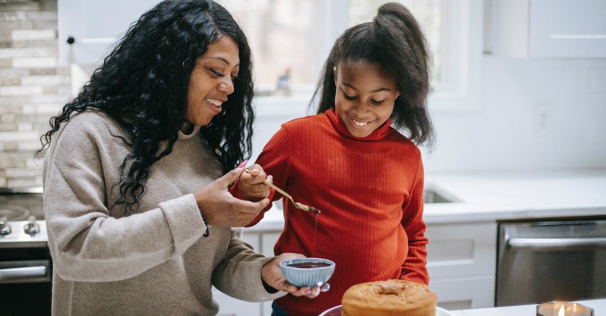 What makes cake a Sponge Cake? And what doesn't? - Young content black woman with girl decorating yummy sponge cake with chocolate glaze during New Year holiday What makes cake a Sponge Cake? And what doesn't? - Young content black woman with girl decorating yummy sponge cake with chocolate glaze during New Year holiday