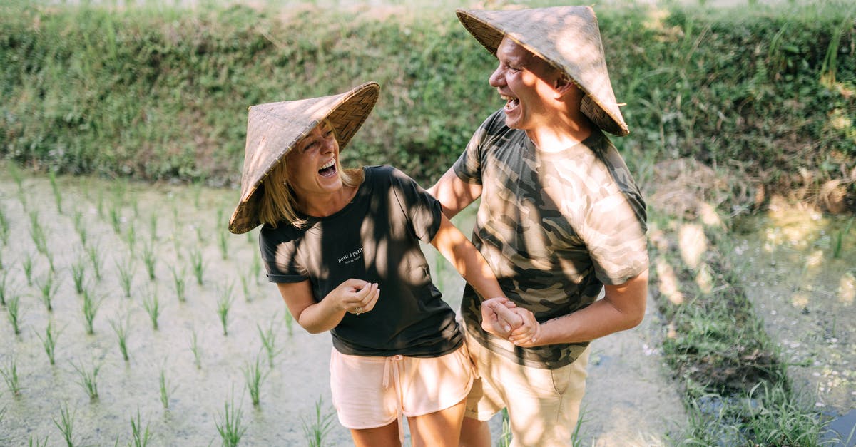 What makes rice wet? - Smiling Couple Standing on Rice Field What makes rice wet? - Smiling Couple Standing on Rice Field