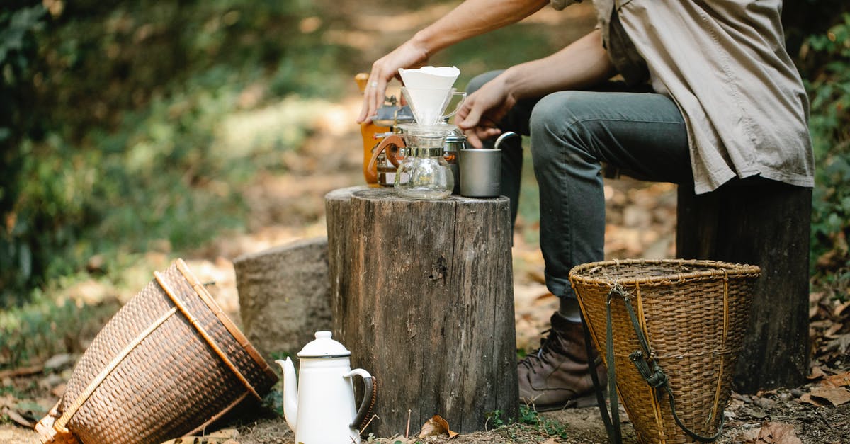 What material is best for a pour over coffee brewer? - Side view of crop anonymous male harvester with manual coffee grinder and pour over maker preparing hot beverage on pathway What material is best for a pour over coffee brewer? - Side view of crop anonymous male harvester with manual coffee grinder and pour over maker preparing hot beverage on pathway