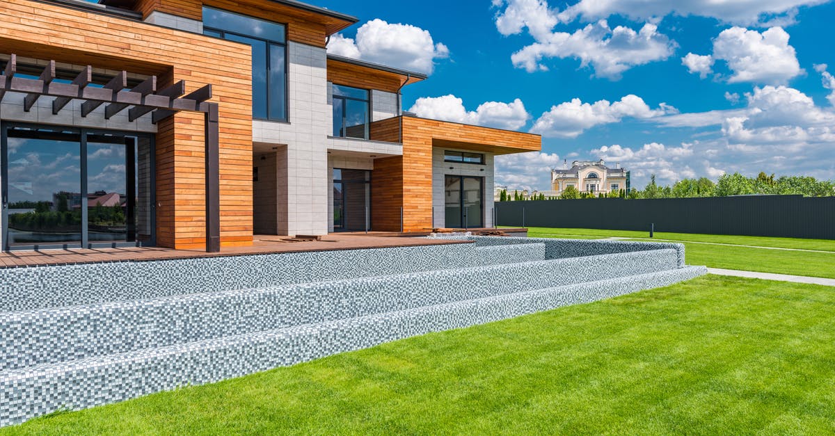 What material wok did I get while thrifting today? - Exterior of contemporary residential house with panoramic windows glass doors and green lawn in yard on sunny day against blue sky with white clouds