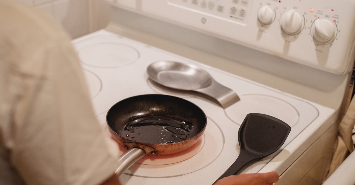 What oil is best for seasoning a cast-iron skillet - Crop unrecognizable person near white stove with black spatula cooking scrambled eggs in kitchen What oil is best for seasoning a cast-iron skillet - Crop unrecognizable person near white stove with black spatula cooking scrambled eggs in kitchen