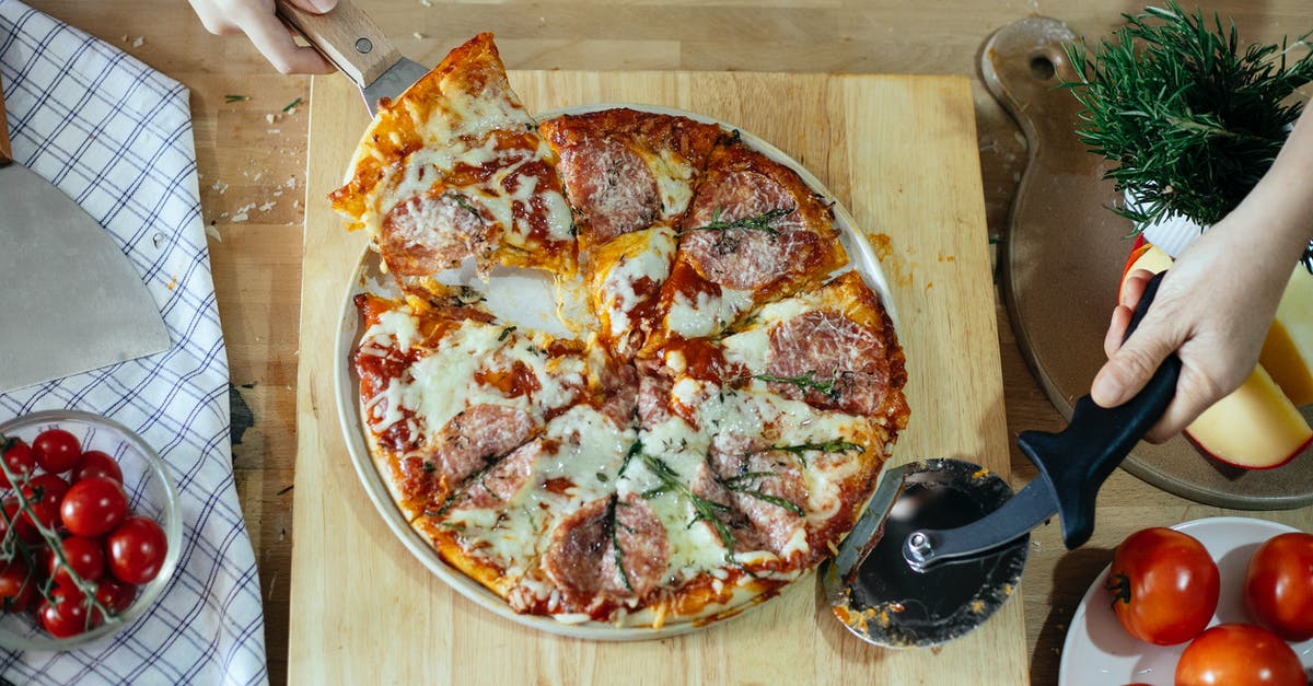What part to use from fresh Basil leaves? - From above unrecognizable women taking slice of pizza with cheese and salami using spatula and cutting with pizza cutter What part to use from fresh Basil leaves? - From above unrecognizable women taking slice of pizza with cheese and salami using spatula and cutting with pizza cutter