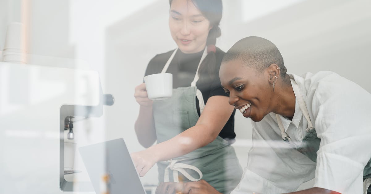 What special knowledge or skills about coffee do baristas have? - Through glass of friendly young Asian head barista showing young cheerful African American female coworker how to use special program on laptop What special knowledge or skills about coffee do baristas have? - Through glass of friendly young Asian head barista showing young cheerful African American female coworker how to use special program on laptop