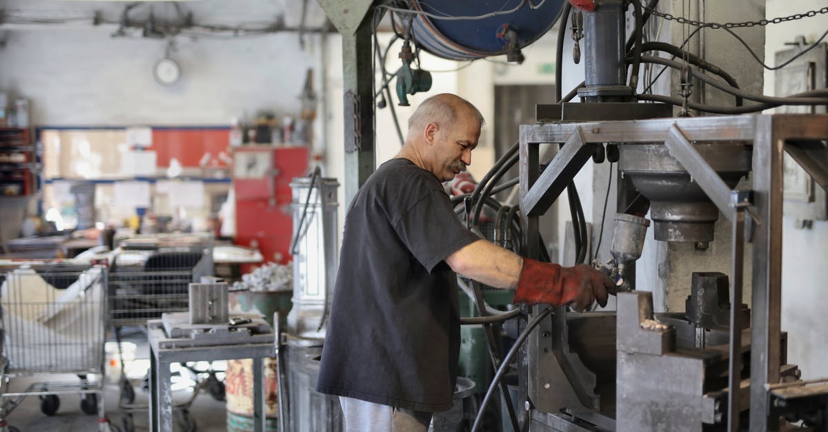 What tempering process do you use when moulding chocolates - Elderly white hair worker using machine What tempering process do you use when moulding chocolates - Elderly white hair worker using machine