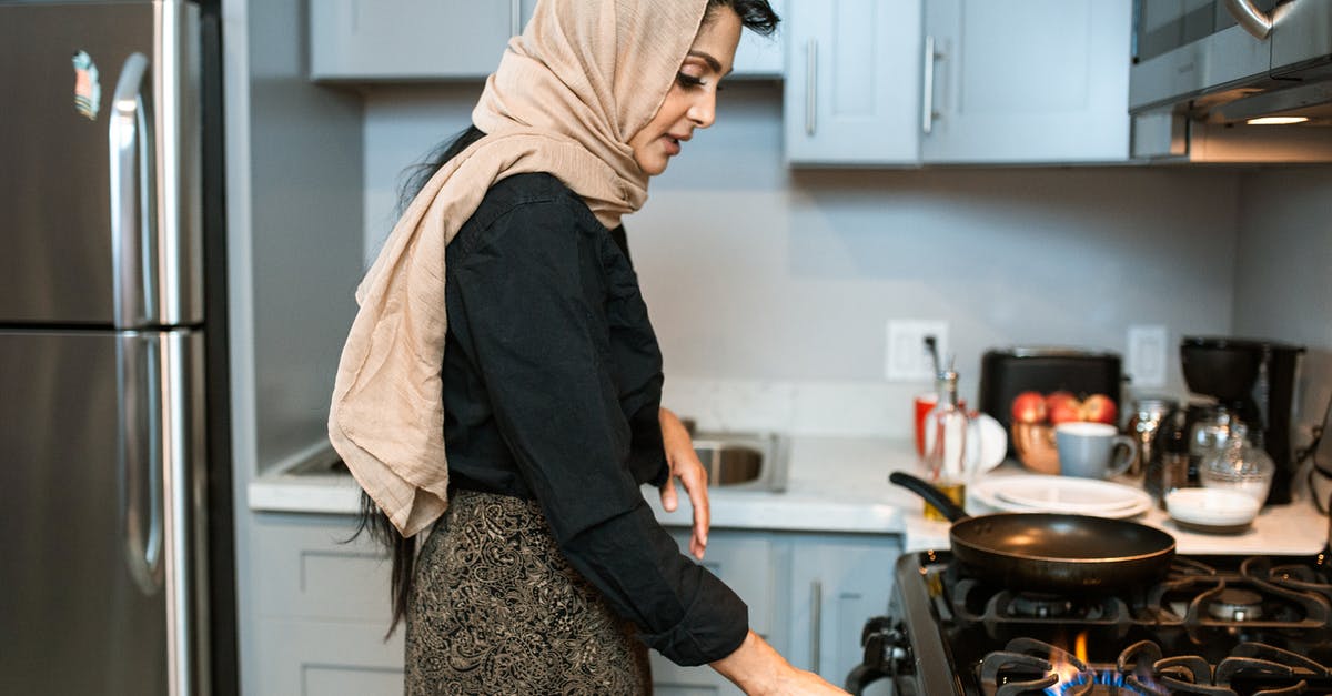 What to do to cool down oven after grease fire? - Ethnic woman in headscarf switching on stove What to do to cool down oven after grease fire? - Ethnic woman in headscarf switching on stove