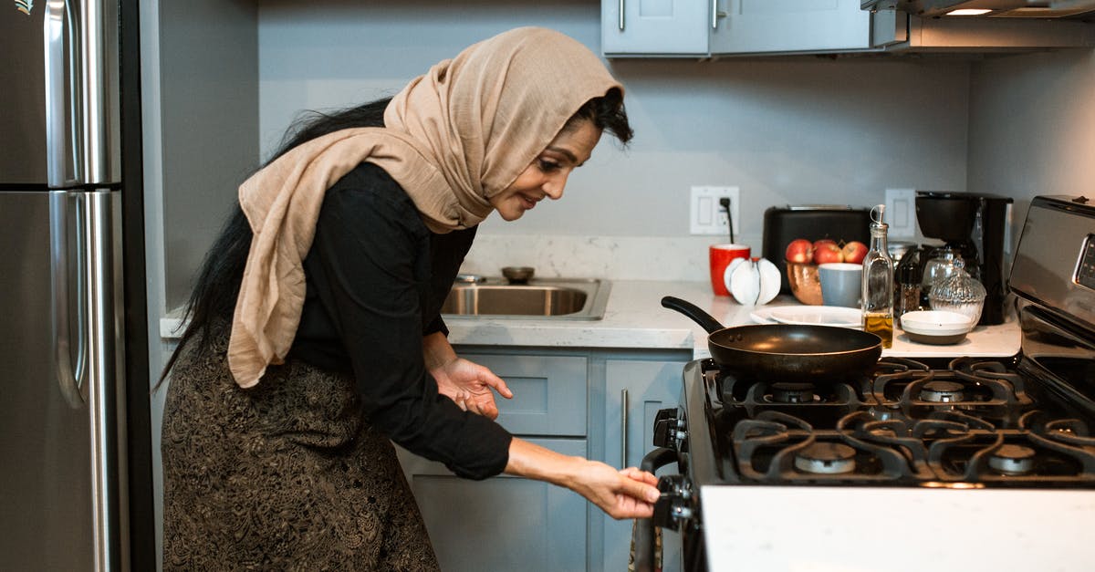 What to do to cool down oven after grease fire? - Cheerful ethnic woman switching stove before cooking What to do to cool down oven after grease fire? - Cheerful ethnic woman switching stove before cooking