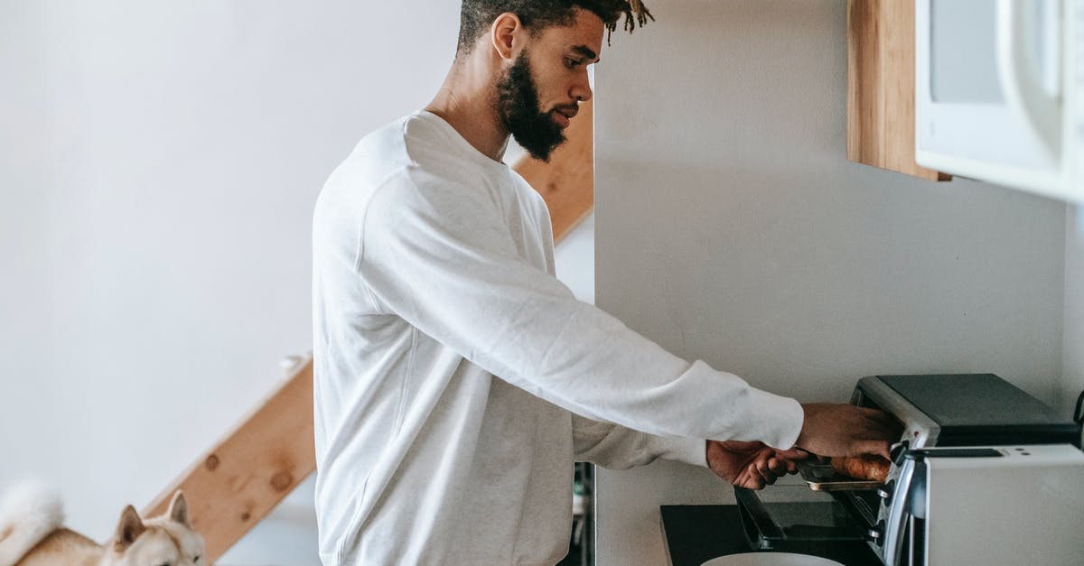 What to do to cool down oven after grease fire? - Bearded young black man heating croissant in microwave oven standing near dog What to do to cool down oven after grease fire? - Bearded young black man heating croissant in microwave oven standing near dog