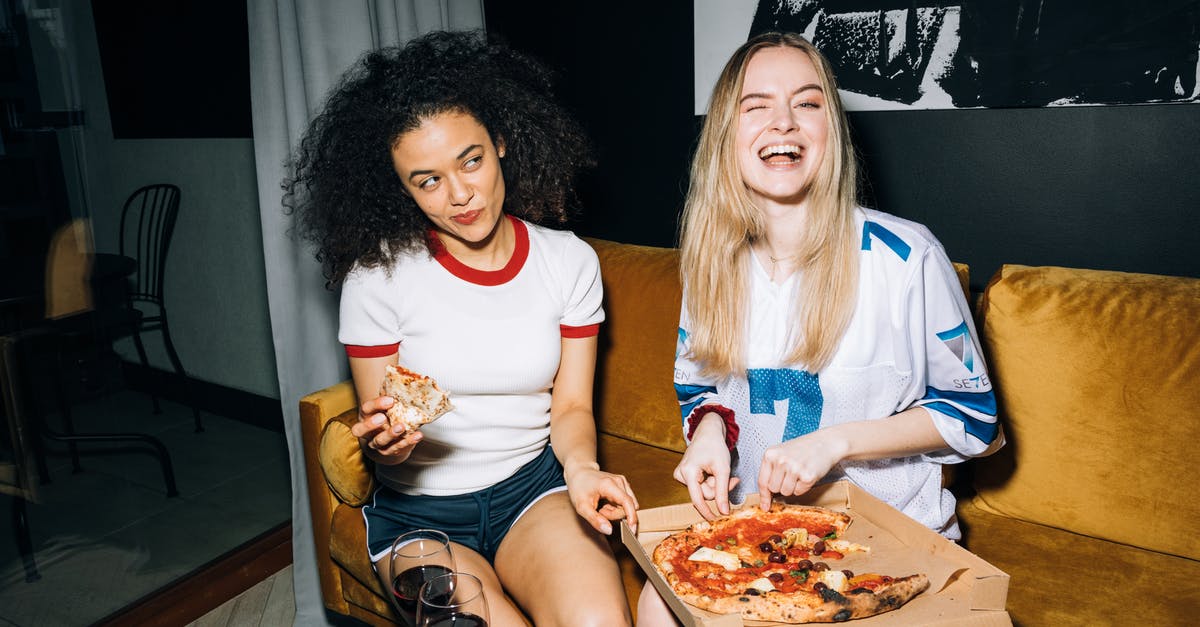 What would be the best way to freeze and reheat home-made pizza - Two Young Women Eating and Getting a Slice of Pizza