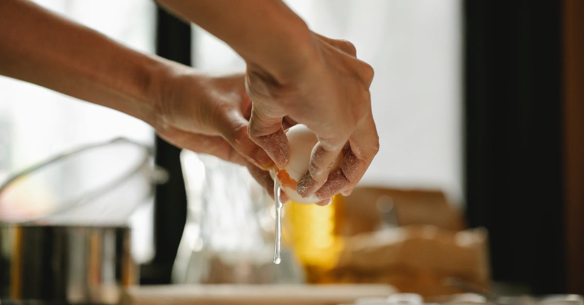 When and how much flour do I add when mixing dough? - Unrecognizable woman cracking egg into flour on table making dough in kitchen on blurred background When and how much flour do I add when mixing dough? - Unrecognizable woman cracking egg into flour on table making dough in kitchen on blurred background