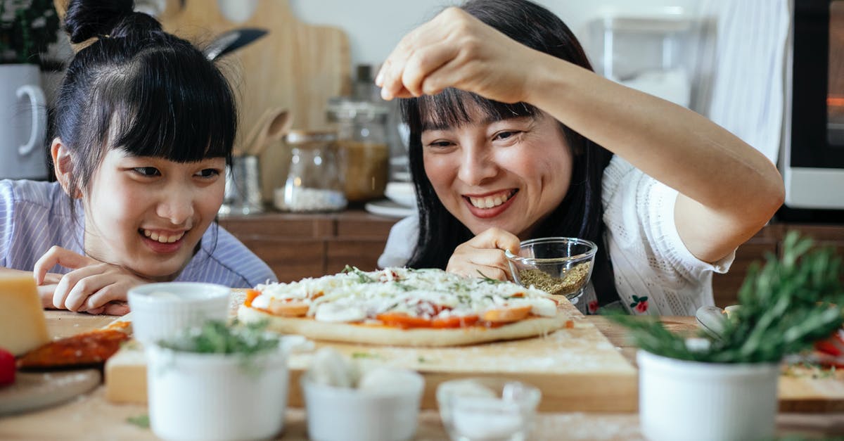 When do you add spices to homemade butter? - Happy women adding spices on pizza When do you add spices to homemade butter? - Happy women adding spices on pizza