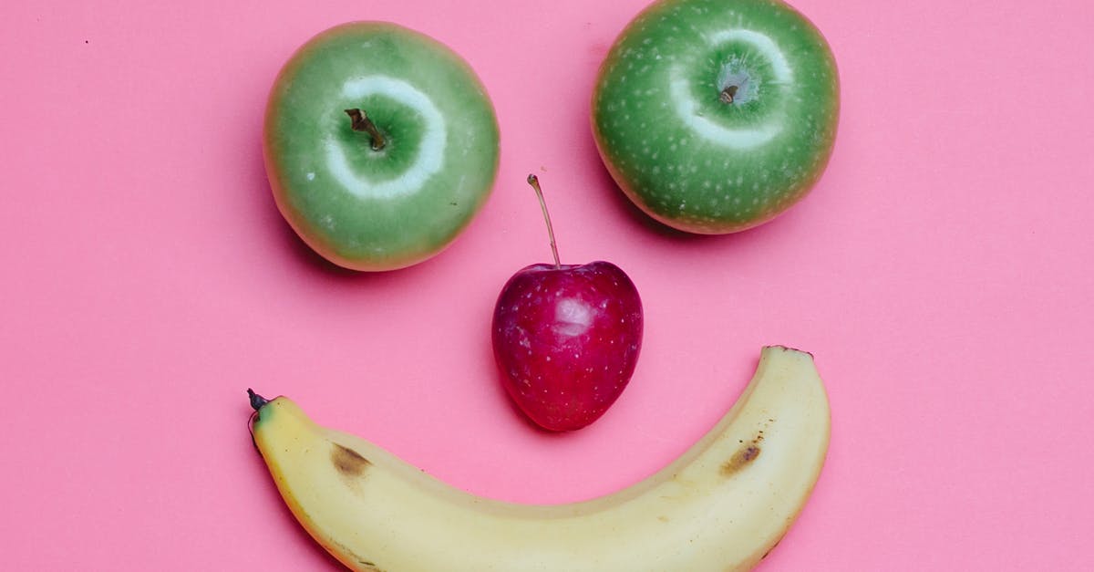 When I make apple juice, what's in the foam on top? - Top view of fresh ripe banana and green and red apples arranged as smile on pink background When I make apple juice, what's in the foam on top? - Top view of fresh ripe banana and green and red apples arranged as smile on pink background