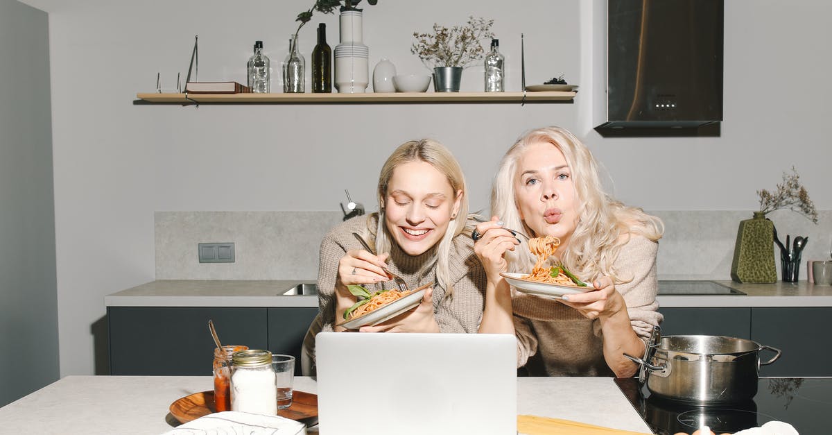 When is a noodle finished cooking [duplicate] - Mother And Daughter Eating Spaghetti in Front of Table With Macbook Air