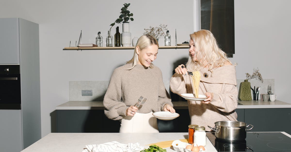 When is a noodle finished cooking [duplicate] - Mother And Daughter Having Spaghetti For Meal