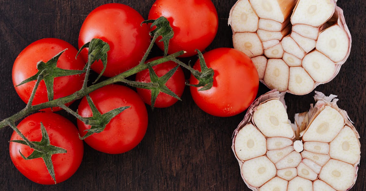 When should I press garlic and when should I chop it? - From above of branch of ripe tomatoes and cut garlic on halves placed on wooden table When should I press garlic and when should I chop it? - From above of branch of ripe tomatoes and cut garlic on halves placed on wooden table