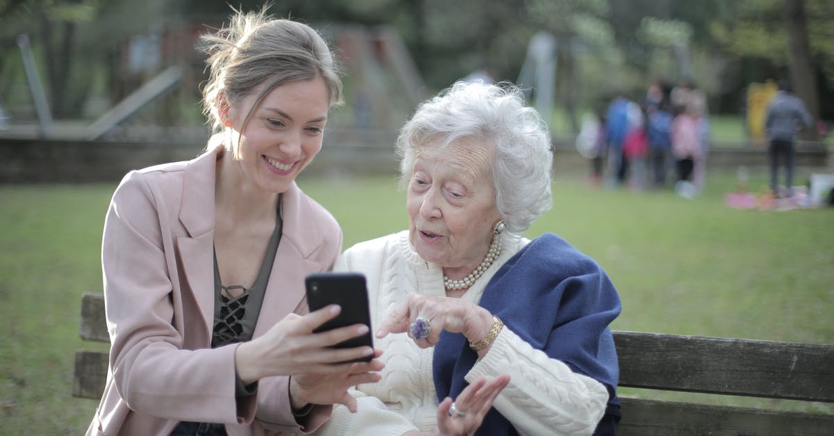 Where to learn what ratios to use in cooking? - Delighted female relatives sitting together on wooden bench in park and browsing mobile phone while learning using Where to learn what ratios to use in cooking? - Delighted female relatives sitting together on wooden bench in park and browsing mobile phone while learning using