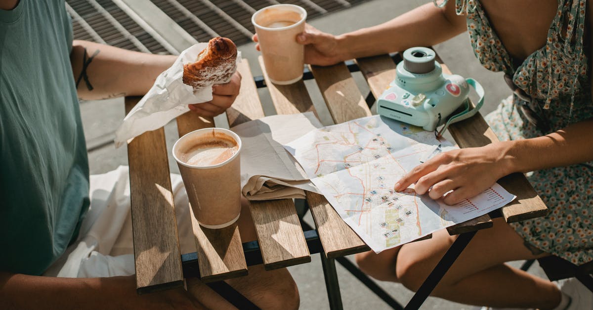 Whetstone with an angle guide - From above of crop anonymous couple searching route in map while having coffee and croissant