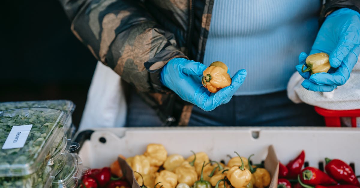 Which mild pepper is a good substitute for Serrano pepper? - Buyer in gloves picking fresh peppers in market Which mild pepper is a good substitute for Serrano pepper? - Buyer in gloves picking fresh peppers in market