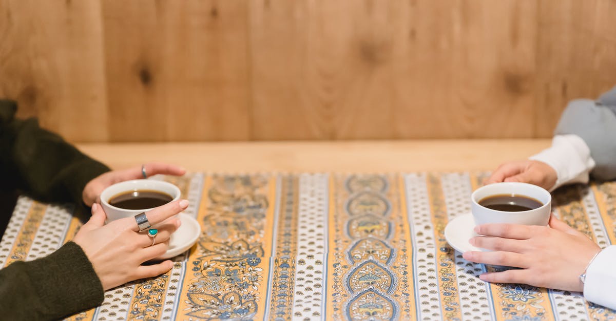 Which part of the coffee brew is best? - Crop faceless women sitting at table with cups of coffee Which part of the coffee brew is best? - Crop faceless women sitting at table with cups of coffee