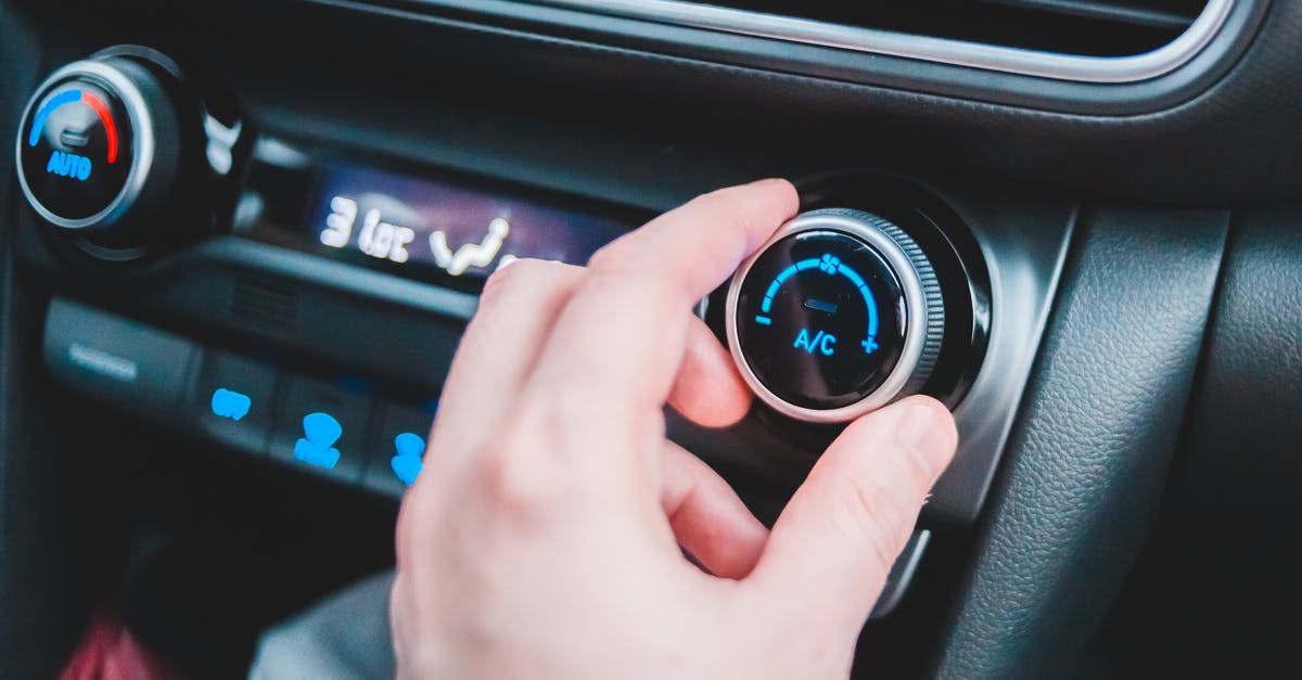 Whole fish oven temperature and inside temperature - Crop anonymous person regulating temperature in car using controller on panel while sitting in car Whole fish oven temperature and inside temperature - Crop anonymous person regulating temperature in car using controller on panel while sitting in car