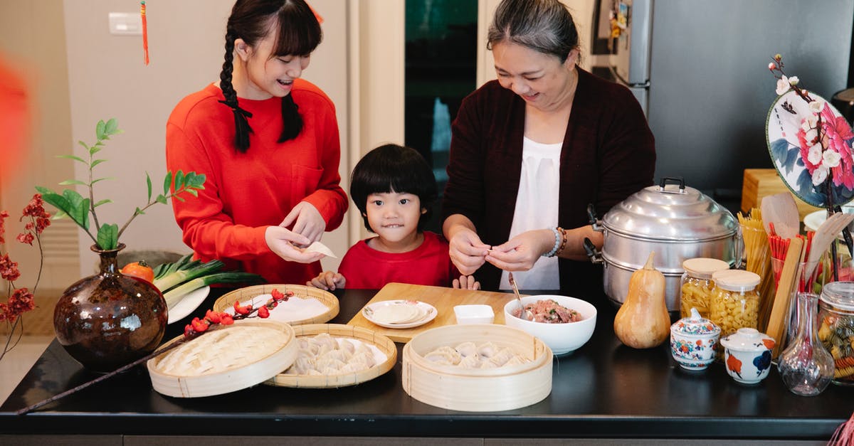 Why are my doughnuts raw in the middle? - Cheerful Asian grandma with boy and female teen preparing dumplings at table with minced beef filling at home Why are my doughnuts raw in the middle? - Cheerful Asian grandma with boy and female teen preparing dumplings at table with minced beef filling at home