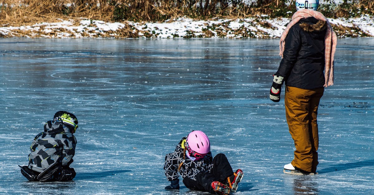 Why do frozen fishes have incision in the body? - Unrecognizable kids with mother playing on icy river in park Why do frozen fishes have incision in the body? - Unrecognizable kids with mother playing on icy river in park