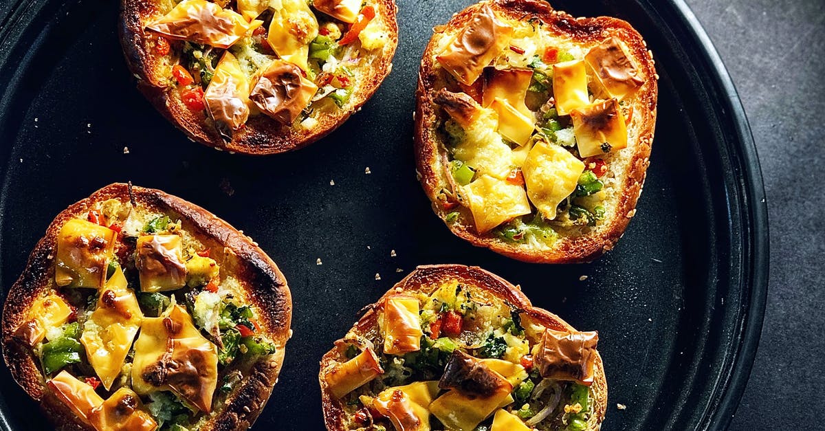 Why do my mini pizzas have microwave trays? - Top view composition of crispy tasty mini bread pizzas with vegetables and cheese served on black tray