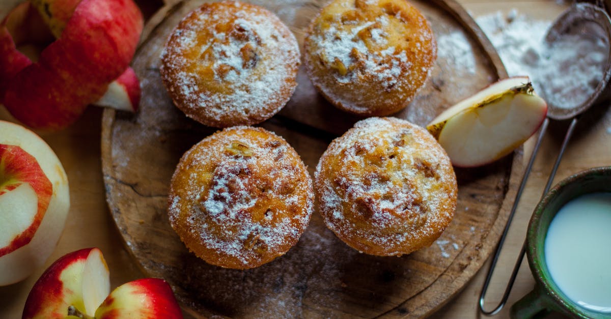 Why do my muffin tops lean? - Top view of delicious baked muffins with powdered sugar placed near cut healthy apples in kitchen Why do my muffin tops lean? - Top view of delicious baked muffins with powdered sugar placed near cut healthy apples in kitchen