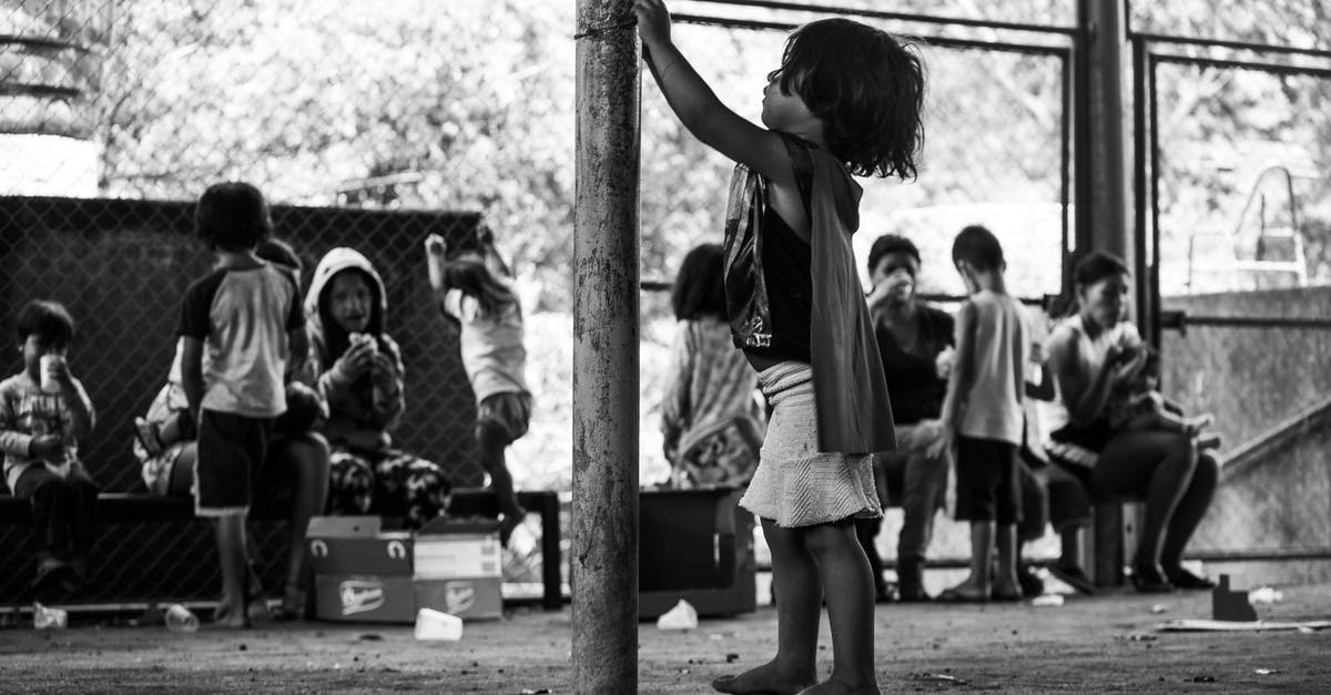 Why do we need to reheat food? - Black and white side view full body of barefoot poor ethnic boy standing near metal pole among people eating food Why do we need to reheat food? - Black and white side view full body of barefoot poor ethnic boy standing near metal pole among people eating food