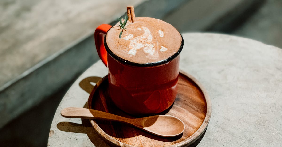 Why does cinnamon in the grounds make older coffee taste better? - From above of delicious coffee with cinnamon and rosemary on wooden plate with spoon placed on wooden table in sunlight