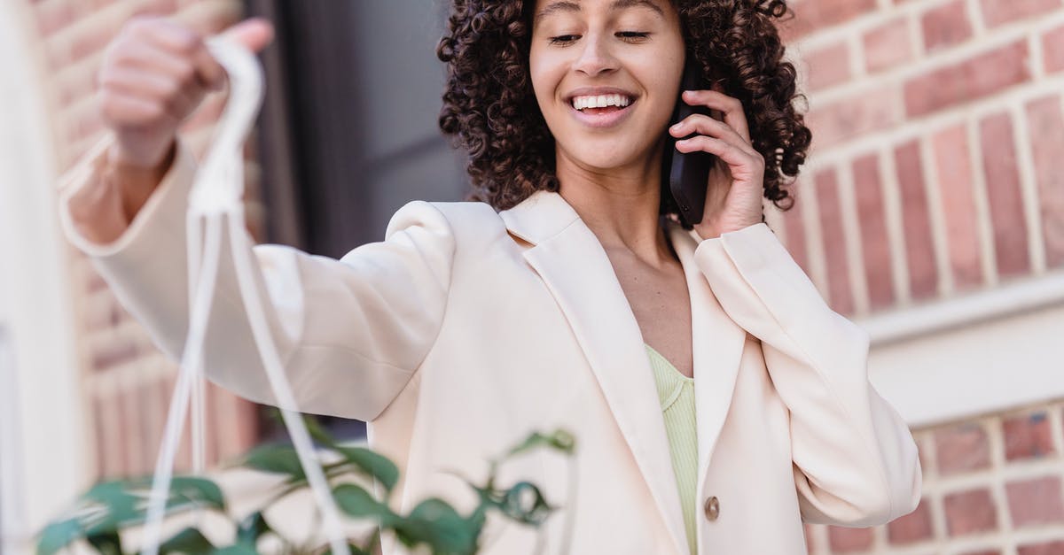 Why does my fondue call to wipe the pot with garlic? - Smiling African American female in white jacket speaking on smartphone and looking at hanging planter outdoors on blurred background Why does my fondue call to wipe the pot with garlic? - Smiling African American female in white jacket speaking on smartphone and looking at hanging planter outdoors on blurred background