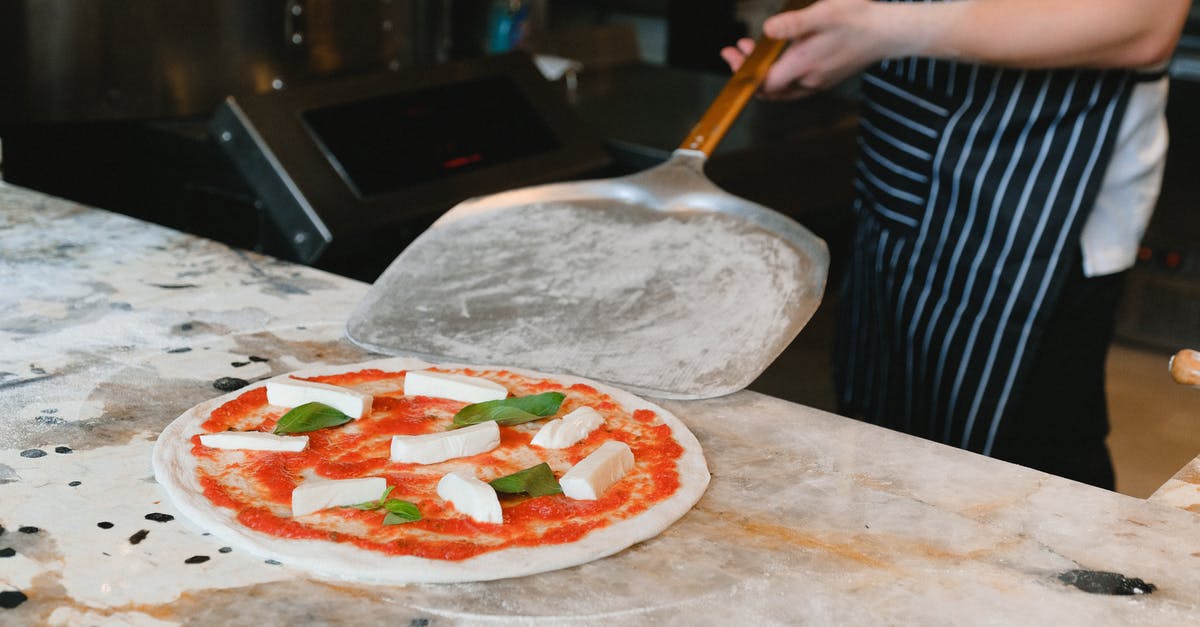Why does my pizza dough stick to my peel? - Person Holding a Peel Beside a Pizza