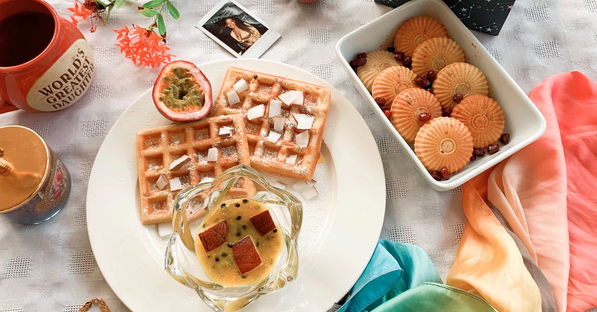 Why does waffle dough get dark? - Top view of composition with plate of baked waffles with jam and exotic fruit placed near cookies and colorful neckerchief and mugs Why does waffle dough get dark? - Top view of composition with plate of baked waffles with jam and exotic fruit placed near cookies and colorful neckerchief and mugs