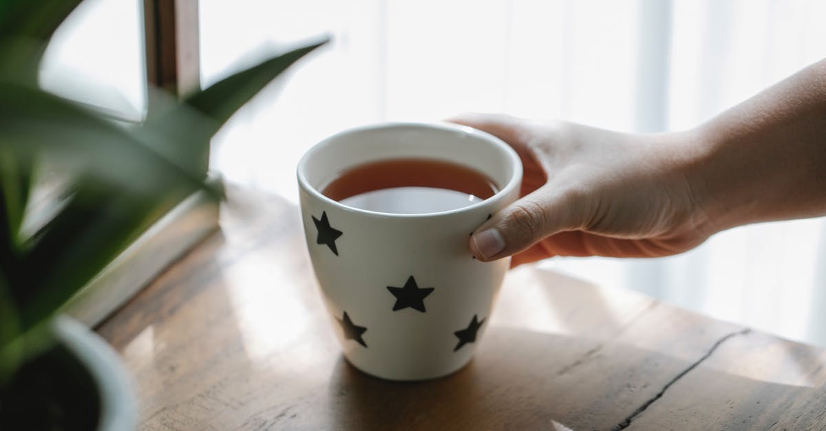 Why is herbal tea brewed at boiling temperature? - High angle of crop faceless person placing mug of hot aromatic delicious tea on wooden table Why is herbal tea brewed at boiling temperature? - High angle of crop faceless person placing mug of hot aromatic delicious tea on wooden table