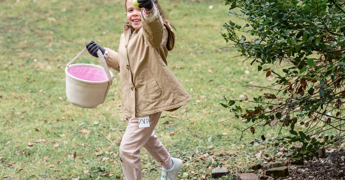 Why is it easier to separate a cold egg? - Full length cheerful girl in warm clothes carrying fabric basket and demonstrating ripe green colored egg or Easter egg in spring park Why is it easier to separate a cold egg? - Full length cheerful girl in warm clothes carrying fabric basket and demonstrating ripe green colored egg or Easter egg in spring park