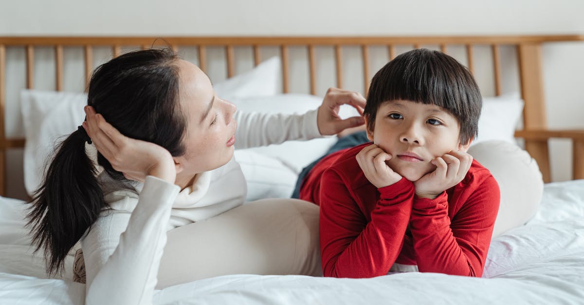 Why is meat sometimes tender and sometimes tough when cooked for a long time? - Tender Asian mother touching hair of cute boy in casual clothes while lying on bed during spare time at home