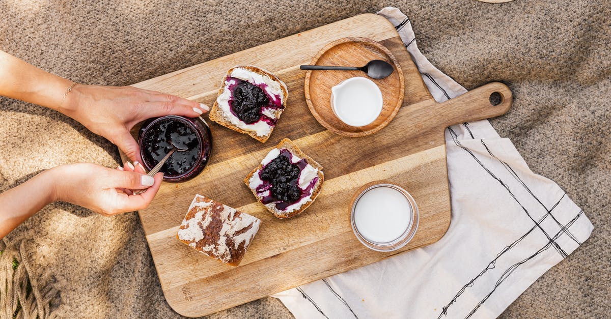 Why is my blueberry jam grainy? - Person Holding Brown Wooden Chopping Board With Sliced of Bread Why is my blueberry jam grainy? - Person Holding Brown Wooden Chopping Board With Sliced of Bread