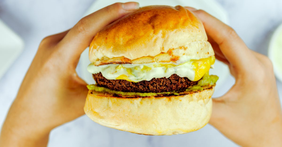 Why is my cheese sauce sweet? - From above of faceless person eating dark brown cutlet between buns in daytime on blurred background Why is my cheese sauce sweet? - From above of faceless person eating dark brown cutlet between buns in daytime on blurred background