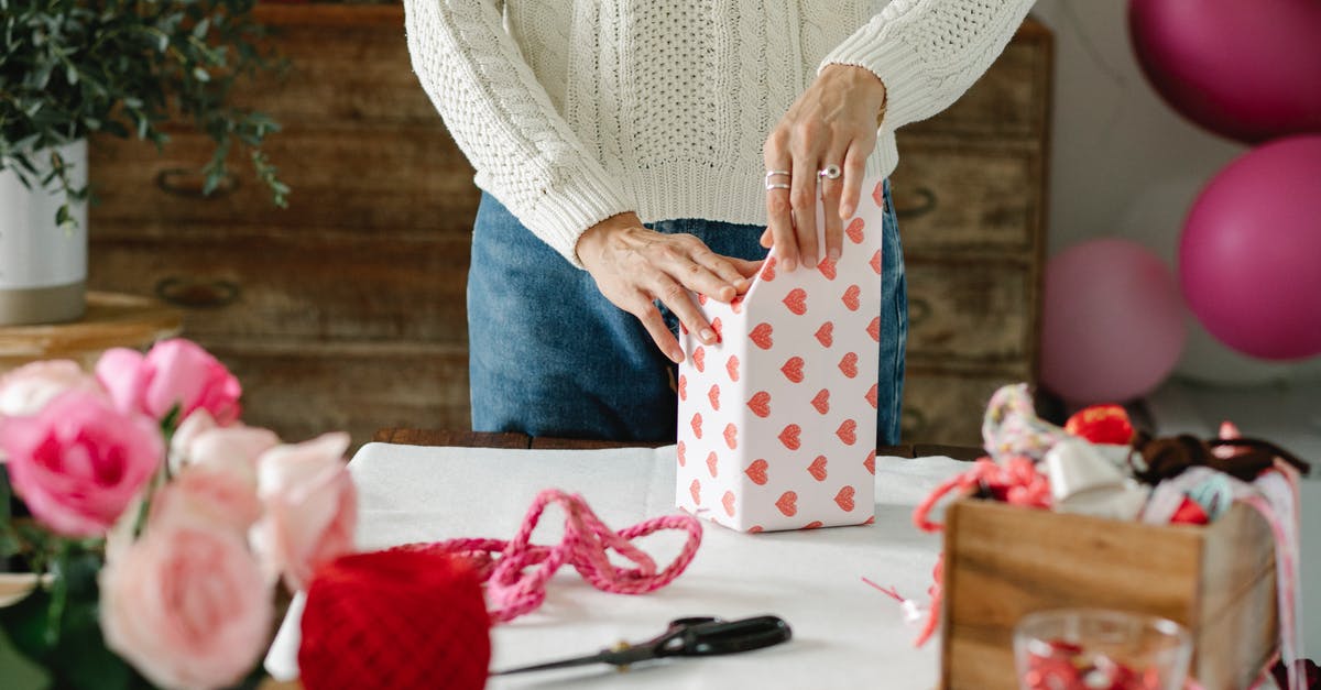 Why is my package of cheese blown up like a balloon - Crop anonymous lady decorating gift box with wrapping paper with red hearts while standing at table with ribbons and flowers Why is my package of cheese blown up like a balloon - Crop anonymous lady decorating gift box with wrapping paper with red hearts while standing at table with ribbons and flowers